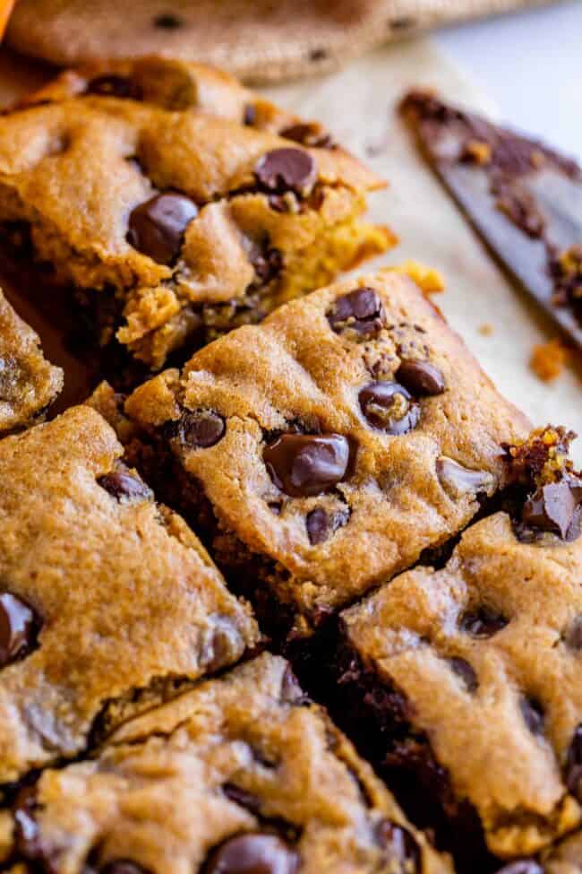 pumpkin bars with chocolate chips on parchment paper with a knife in the background