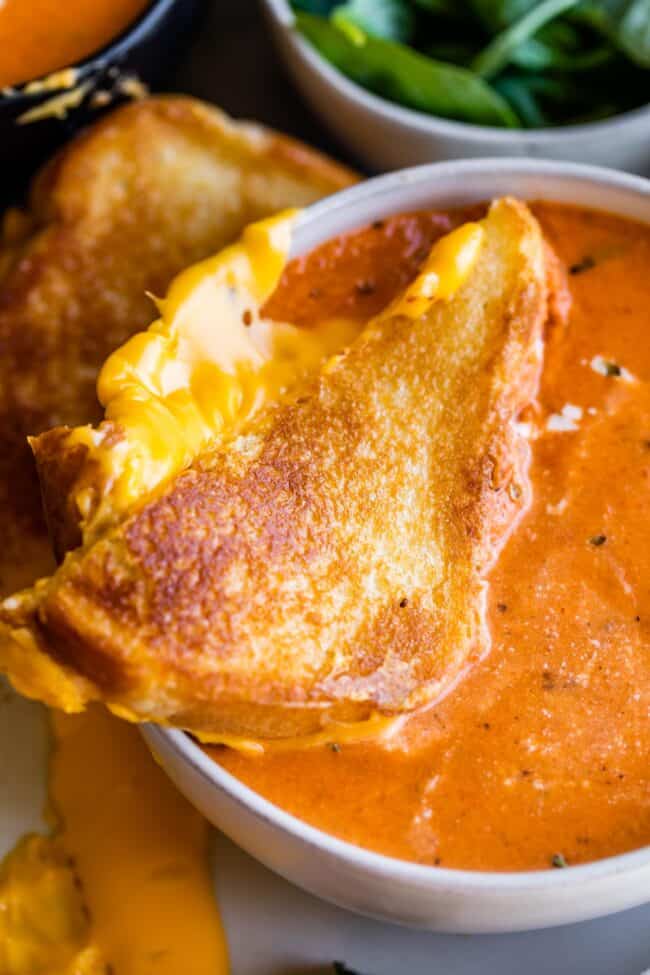 bowl of creamy tomato soup with grilled cheese triangle on top, floating.