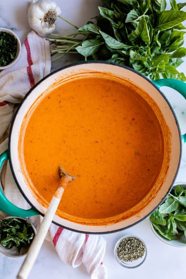 Homemade cream tomato soup in a crockpot with a wooden spoon.