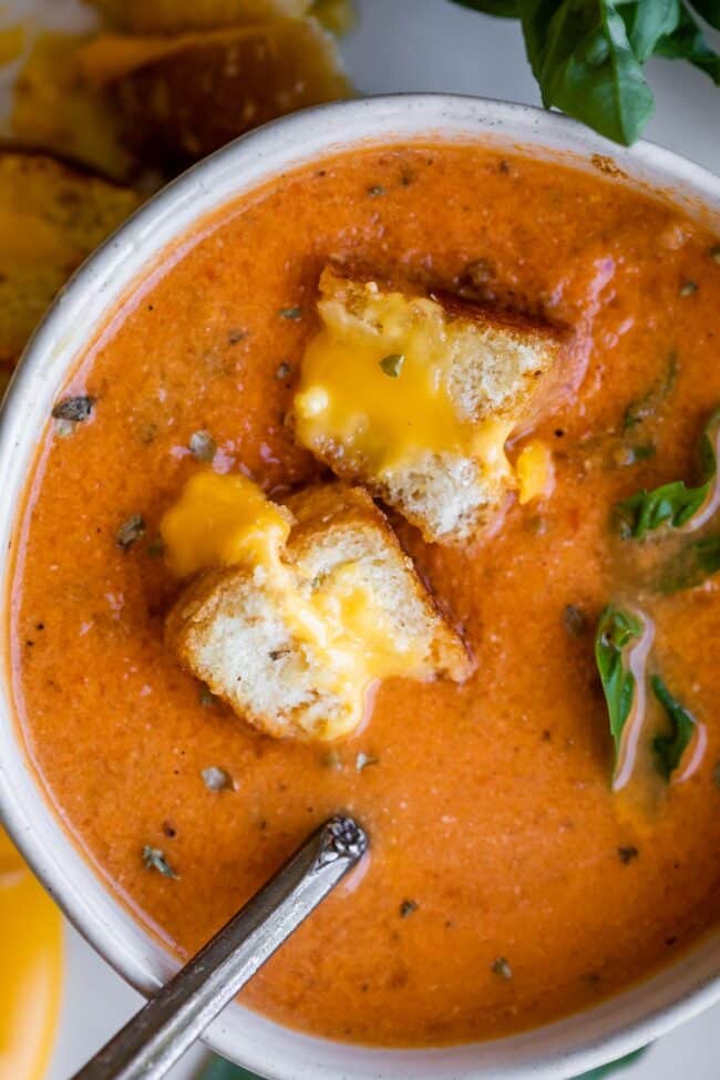 Soup in bowl showing hot to make tomato soup, with grilled cheese bits floating above