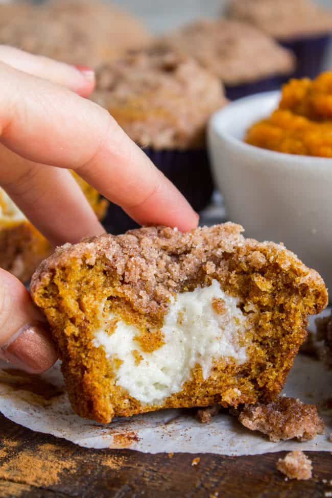 pumpkin cream cheese muffin being picked up, cut in half.