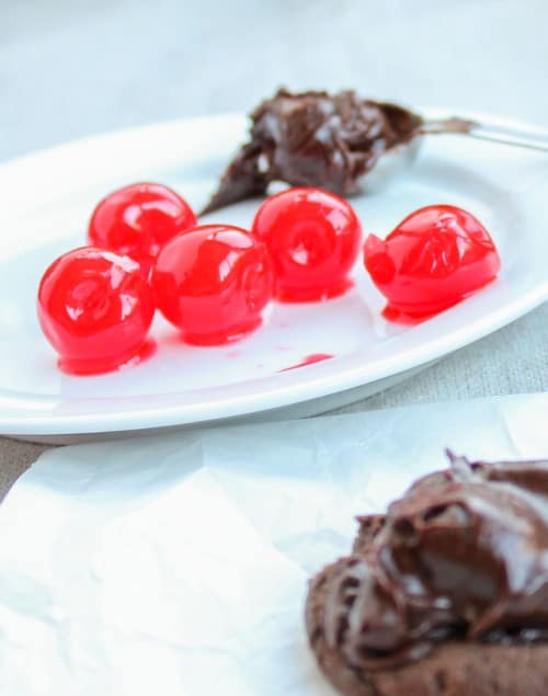 Maraschino cherries next to chocolate cookie