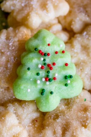 green almond spritz cookie in a tree shape with sprinkles on top