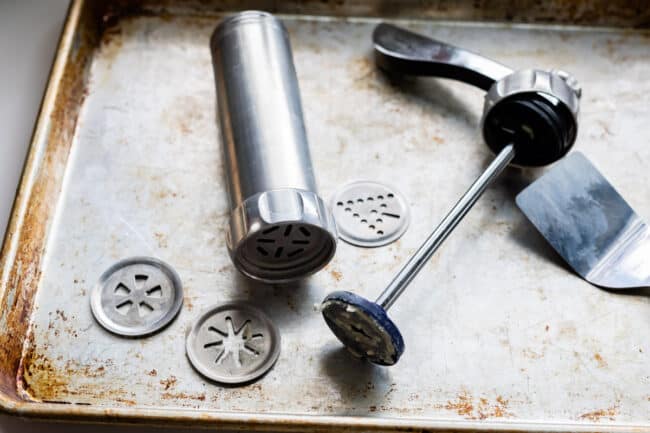 metal cookie press on a baking sheet.