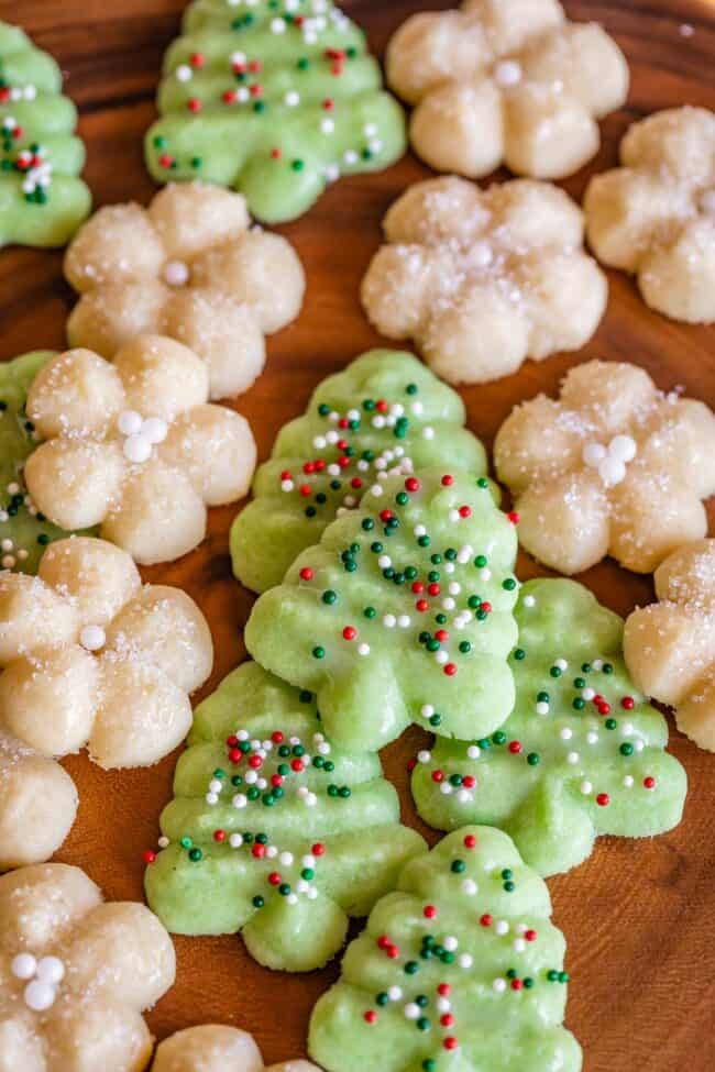 green and white Spritz cookies decorated with sprinkles on a wooden board.