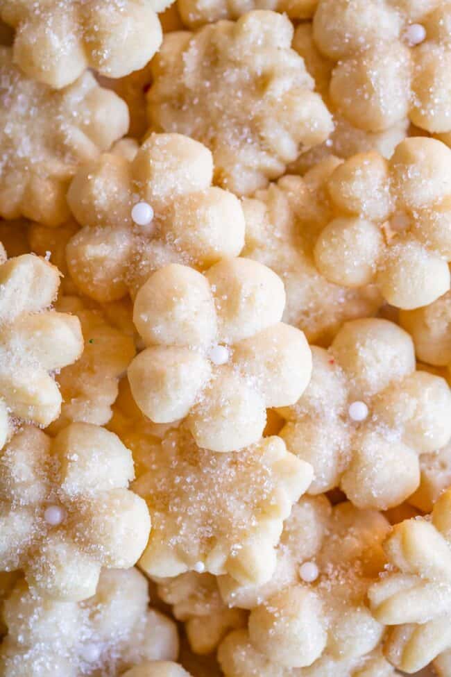 buttery golden spritz cookies, piled on a baking sheet and decorated with sprinkles.