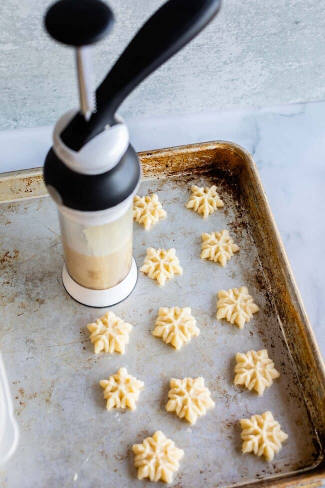 pressing spritz cookie dough in snowflake shapes through a press onto an ungreased baking sheet.