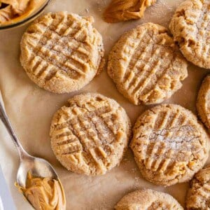 best peanut butter cookies on a sheet of brown parchment paper with a spoonful of peanut butter