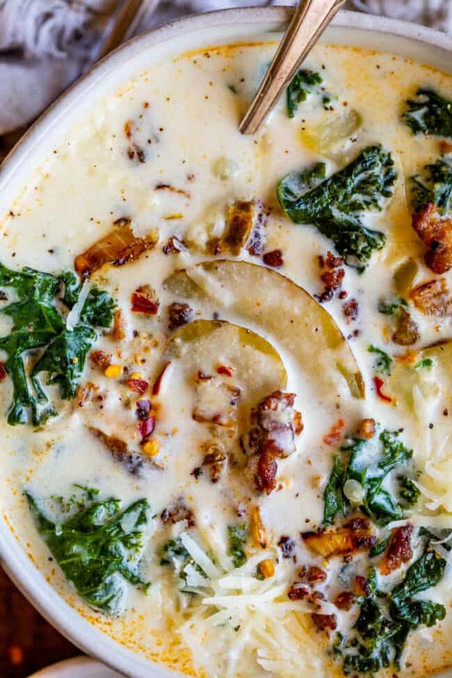 Zuppa Toscana recipe in a white bowl with spoon and Italian sausage