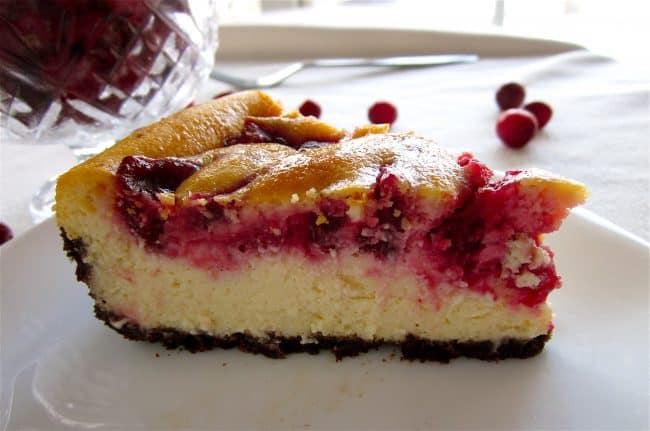 Cranberry cheesecake on plate with cranberries in background
