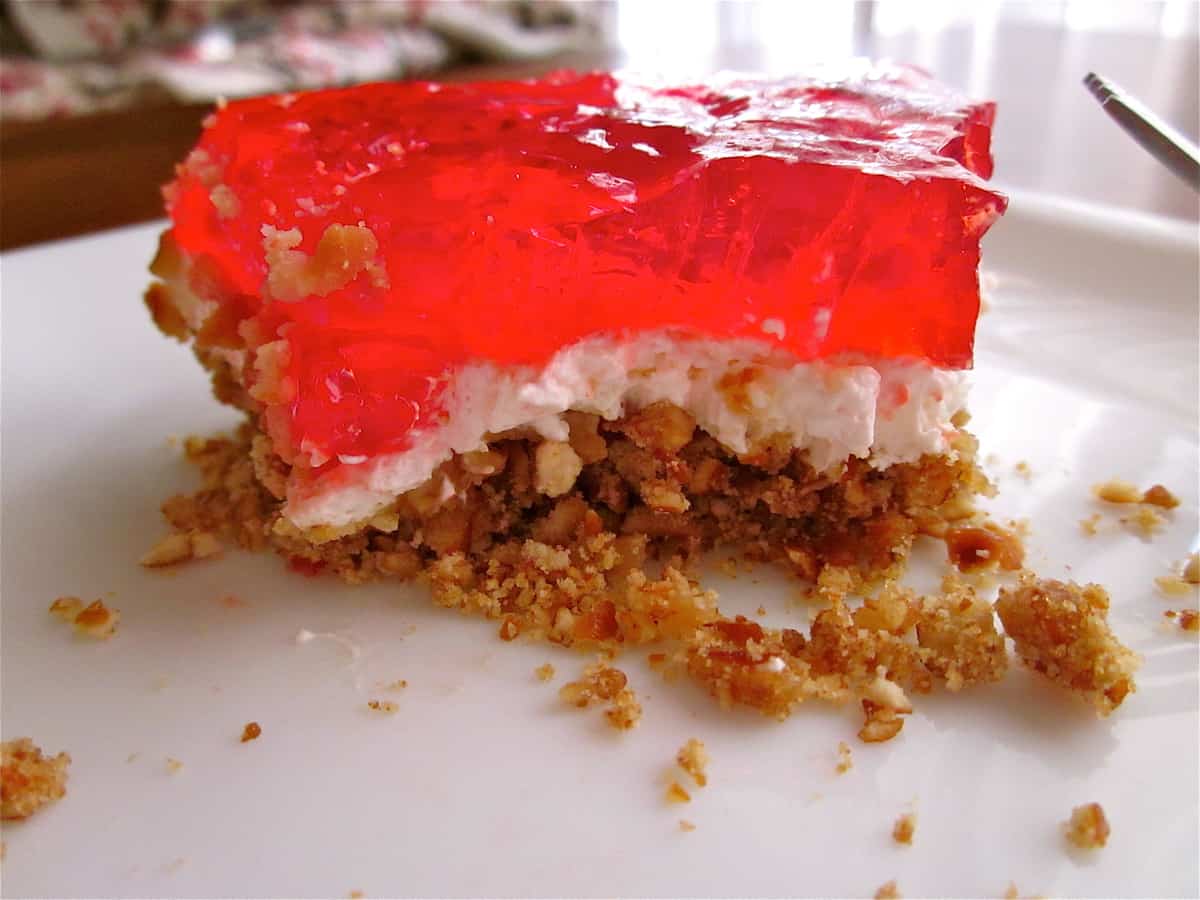 IMG_1874 Old photo of strawberry jello, creamy filling and pretzel crust on a white plate.