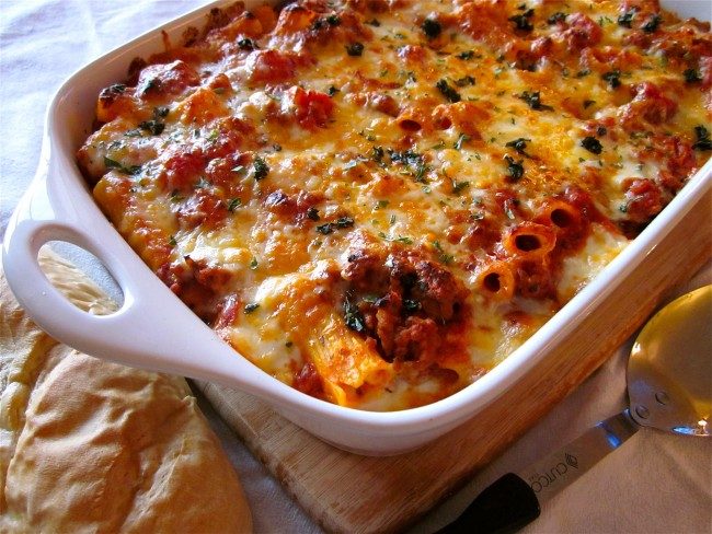 cheesy baked ziti in a white baking dish.