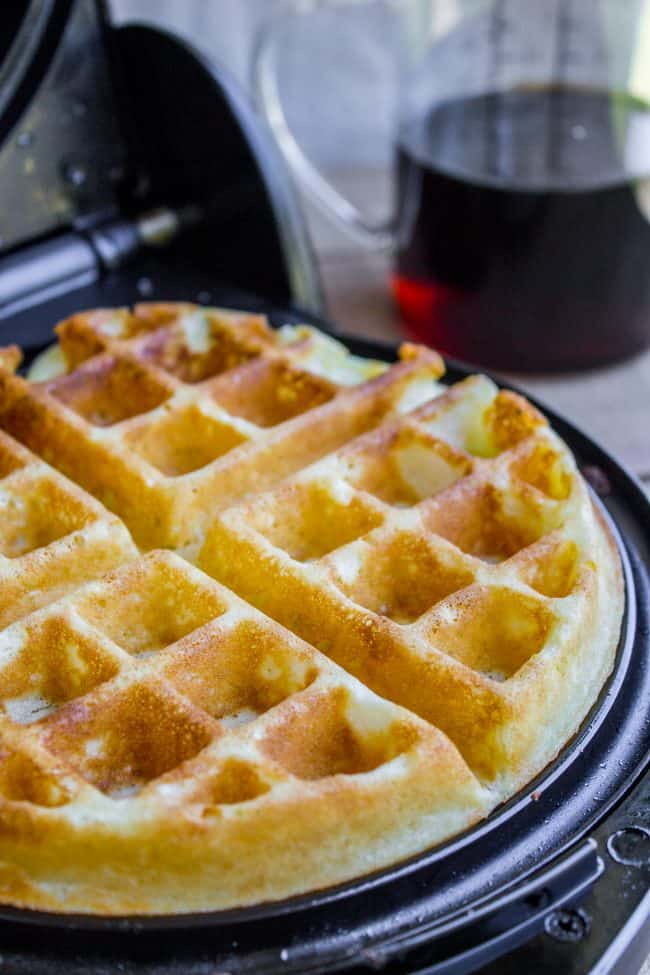 a crisp waffle just finished cooking in a waffle iron. 