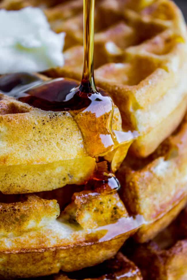 pouring syrup on a stack of waffles.