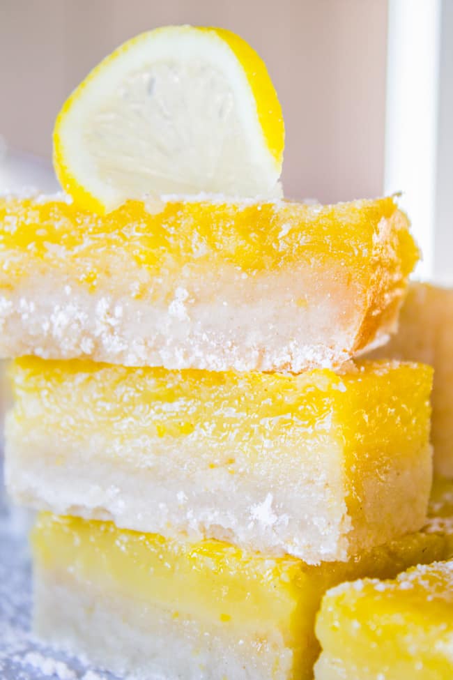 a stack of lemon squares with a thick shortbread crust.