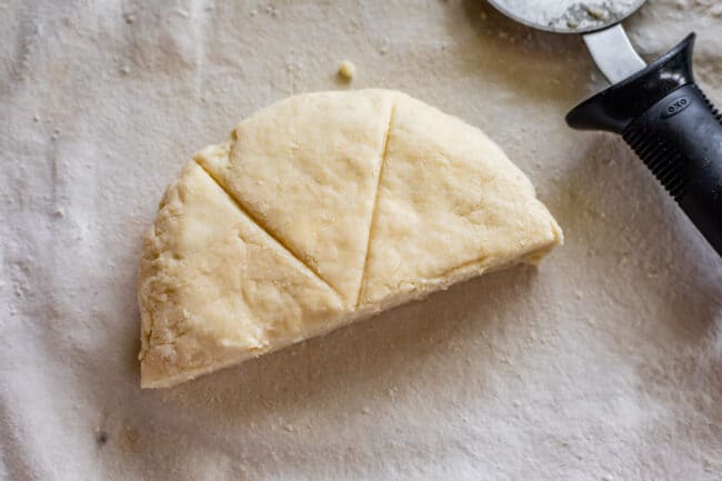 slicing scones for baking showing a half-circle of dough.