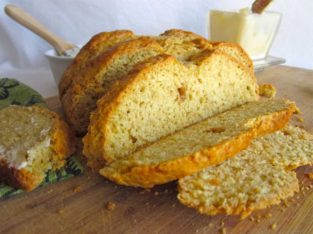 Sliced Irish soda bread on a wooden cutting board with butter in the background.