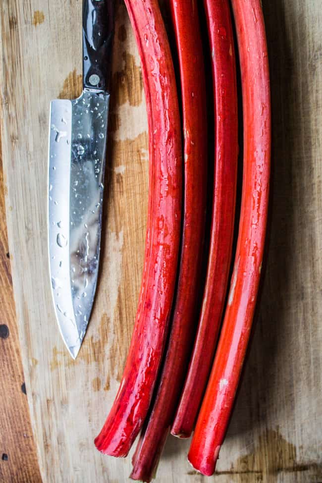 Dark red rhubarb on cutting board with chef's knife