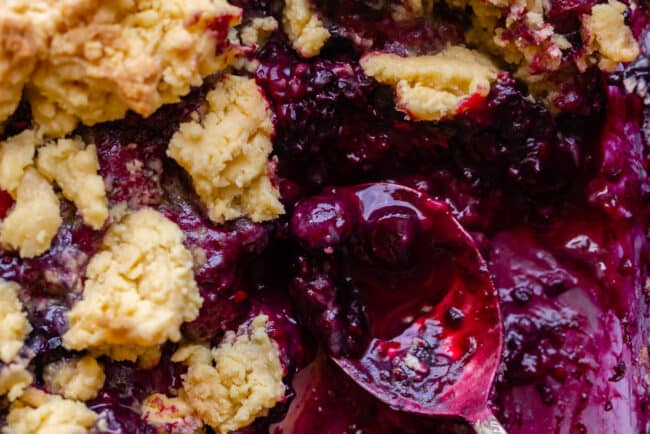 frozen berry cobbler after baking with spoon inside pan