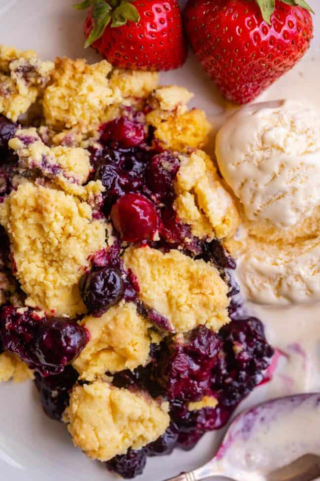 mixed berry cobbler with cake mix on a plate with ice cream.