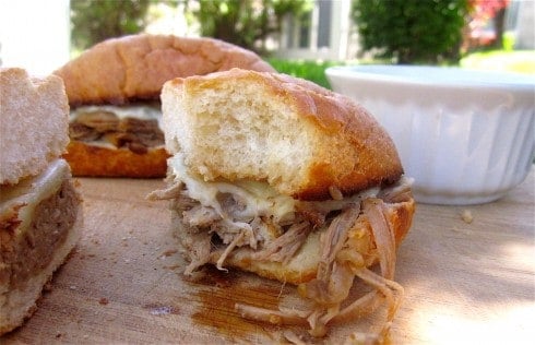 Half of french dip sandwich with bite out of it and full sandwich in the background.