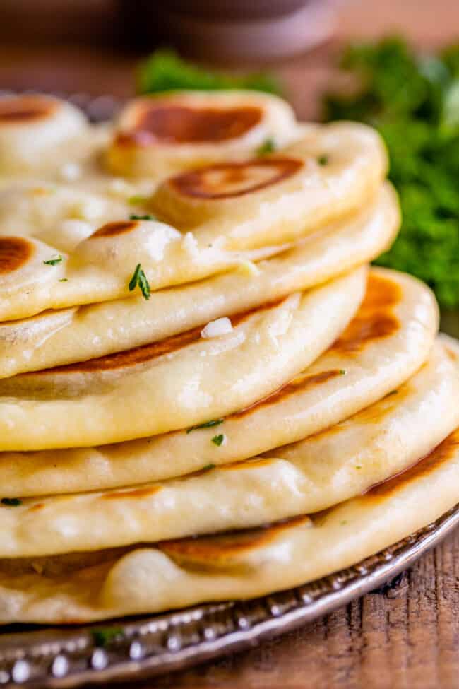 fresh homemade buttery naan, stacked on a plate.