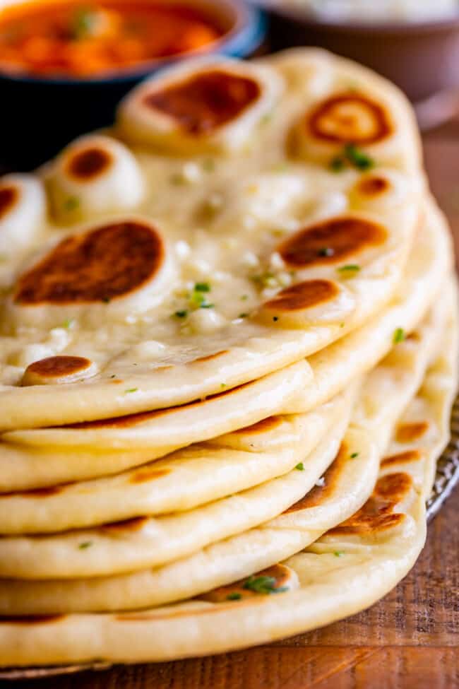 freshly buttered naan bread stacked on a plate.