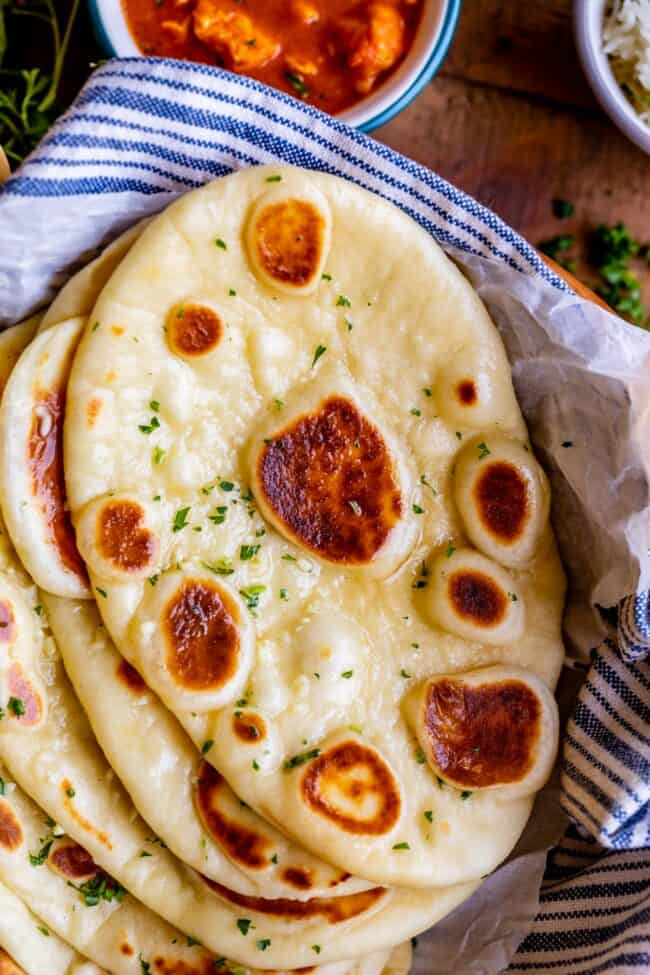 buttery naan with fresh parsley, stacked on a blue and white striped napkin.