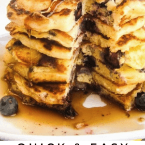 A stack of lemon blueberry pancakes topped with fresh blueberries, banana slices, and dripping syrup. The pancakes are cut to show their fluffy interior. Text reads: “Quick & Easy Lemon Blueberry Pancakes with a burst of citrus flavor.”.