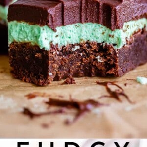 A close-up of fudgy mint brownies with a thick mint layer and chocolate ganache on top. One brownie has a bite taken out. Text at the bottom reads, Fudgy Chocolate Mint Brownies.
