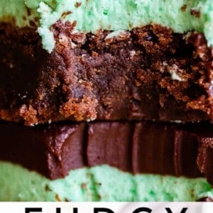 Close-up of two stacked fudgy mint brownies with a thick layer of green mint cream, topped with glossy chocolate ganache. Text at the bottom reads Fudgy Chocolate Mint Brownies.