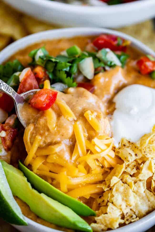 Creamy Chicken Enchilada Soup (Chili's Copycat Recipe) from The Food Charlatan. This dreamy Creamy Chicken Enchilada Soup tastes like the kind at Chili's, only better! It is a simple soup that has a unique flavor thanks to Masa Harina (corn flour). There are no veggies in the soup; instead you make Pico de Gallo and serve it as a generous topping! It's one of my all time favorite soups! #chicken #dinner #recipe #easy #enchilada #enchiladasoup #chickensoup #creamy #cheesy #stovetop #Chilis chicken enchilada soup garnished with cheese, chips, avocado, sour cream, and pico de gallo.