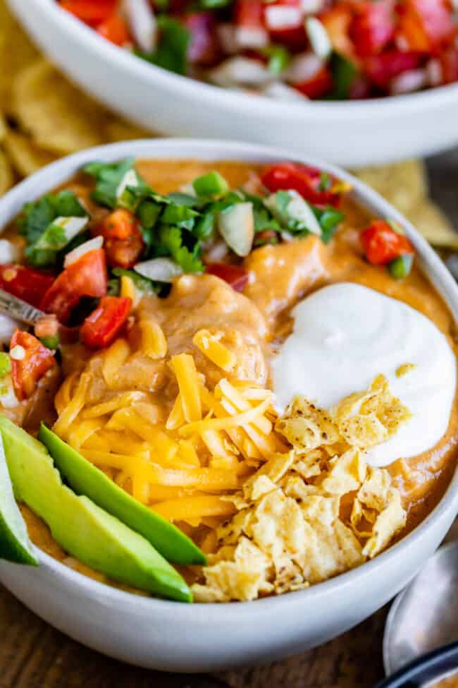 Creamy Chicken Enchilada Soup (Chili's Copycat Recipe) from The Food Charlatan. This dreamy Creamy Chicken Enchilada Soup tastes like the kind at Chili's, only better! It is a simple soup that has a unique flavor thanks to Masa Harina (corn flour). There are no veggies in the soup; instead you make Pico de Gallo and serve it as a generous topping! It's one of my all time favorite soups! #chicken #dinner #recipe #easy #enchilada #enchiladasoup #chickensoup #creamy #cheesy #stovetop #Chilis chicken enchilada soup with garnishes.