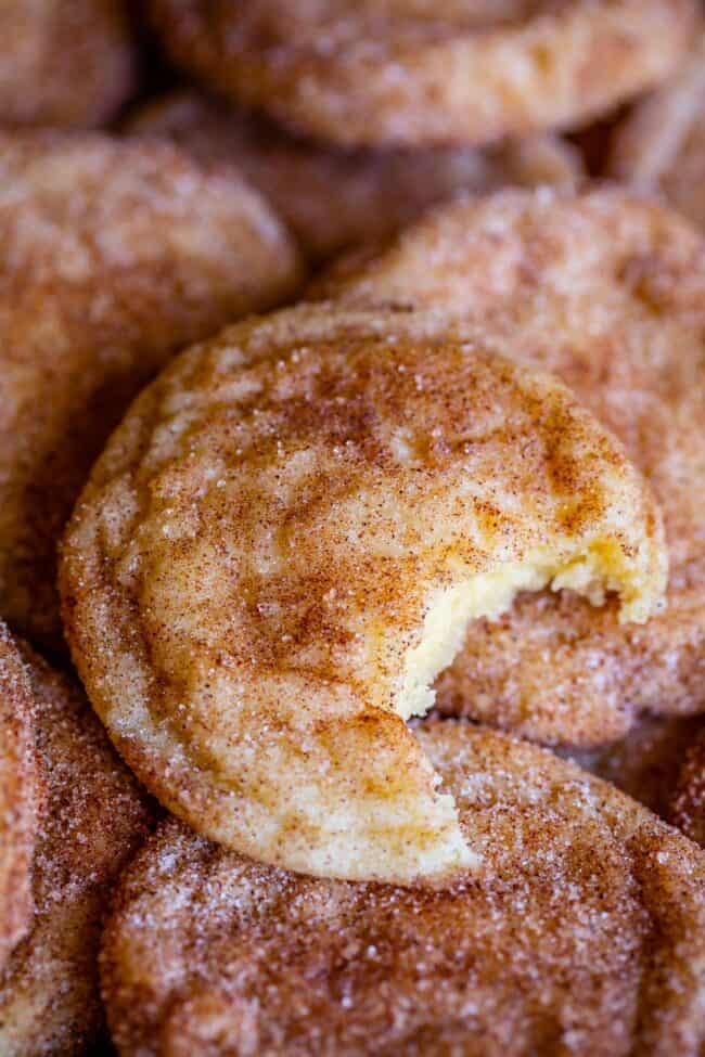 snickerdoodle cookie with a bite taken out on top of other snickerdoodles.