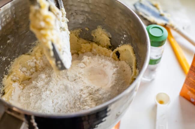 dry ingredients being added to cookie dough in a stand mixer.