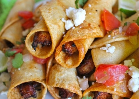 a close up shot of homemade chicken flautas with pico de gallo and queso fresco.