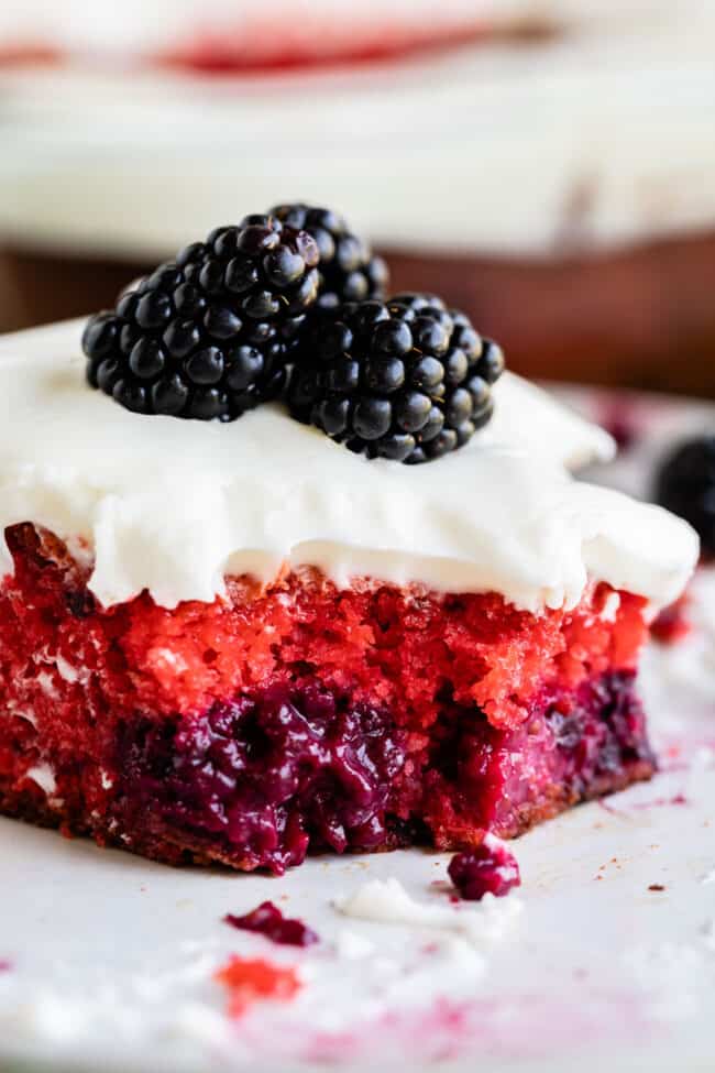 Blackberry cake with coconut cream cheese frosting and berries on top.