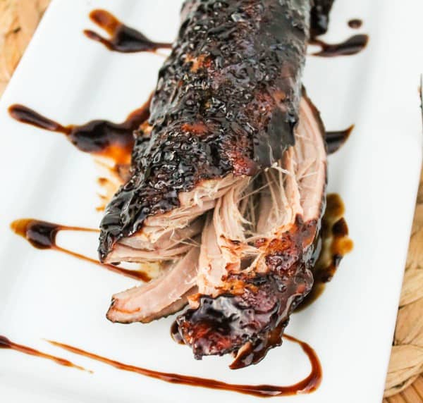 a white serving platter with glazed slow cooker pork tenderloin.