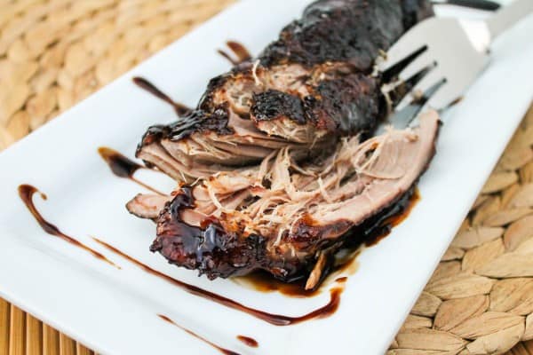 brown sugar balsamic pork tenderloin on a white serving platter with a fork.