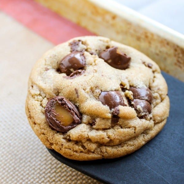 a single butterscotch cookie with chocolate caramels on a baking sheet. 