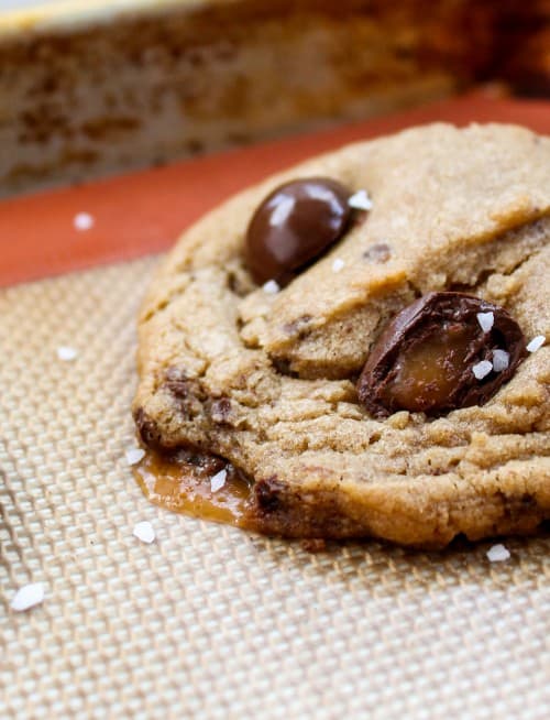 caramel melting out of a butterscotch caramel cookie onto a silcone baking mat. 