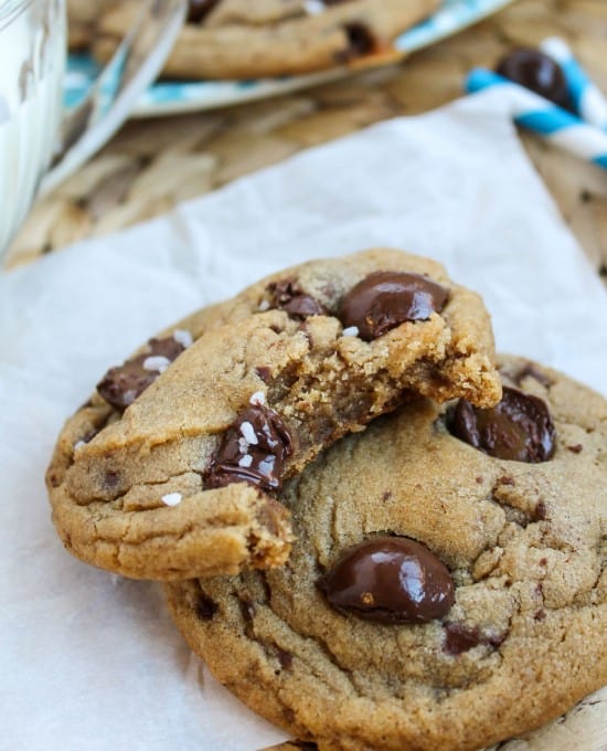 butterscotch caramel cookies on parchment paper, one with a bite taken out of it. 