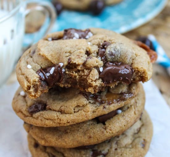 a stack of caramel butterscotch cookies next to a glass of milk. 