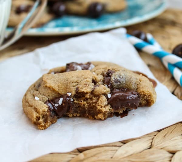 caramel butterscotch cookie on a square of parchment paper next to striped straws. 