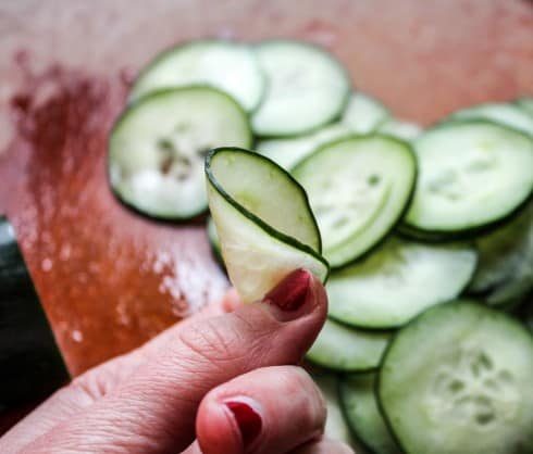 hand showing flexibility of a thin cucumber slice.