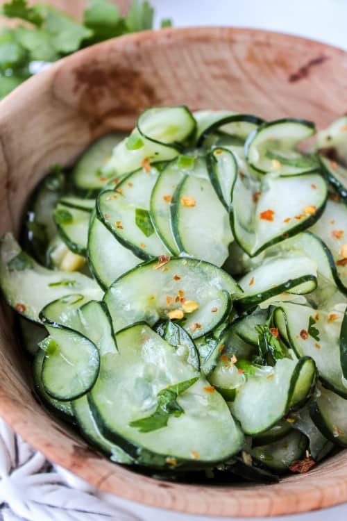Mexican cucumber salad with cilantro and lime in a wooden bowl.