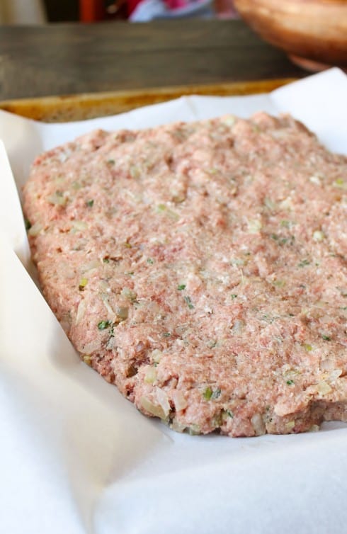 raw meatloaf shaped and ready to bake on a parchment lined baking sheet.