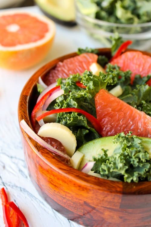 grapefruit and kale salad in wooden bowl