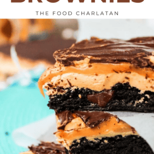 A close-up of stacked snickers brownies topped with rich chocolate and caramel layers on parchment paper, with Make The Best Snickers Brownies text above.