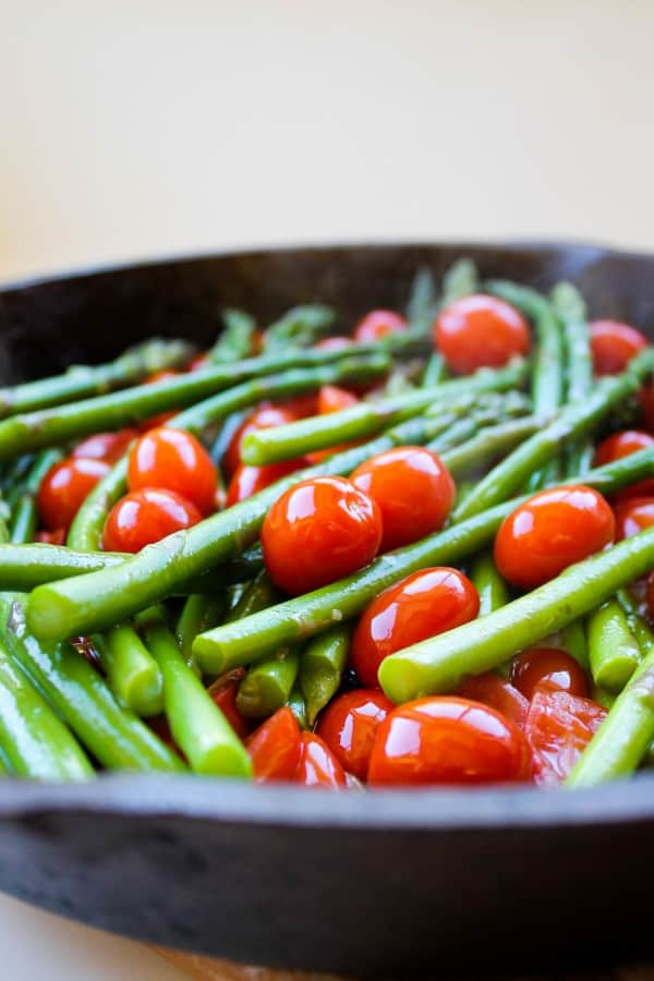 asparagus and cherry tomatoes in a cast iron skillet.